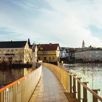 A wide view of a road leading past white apartment buildings in a green hillside.