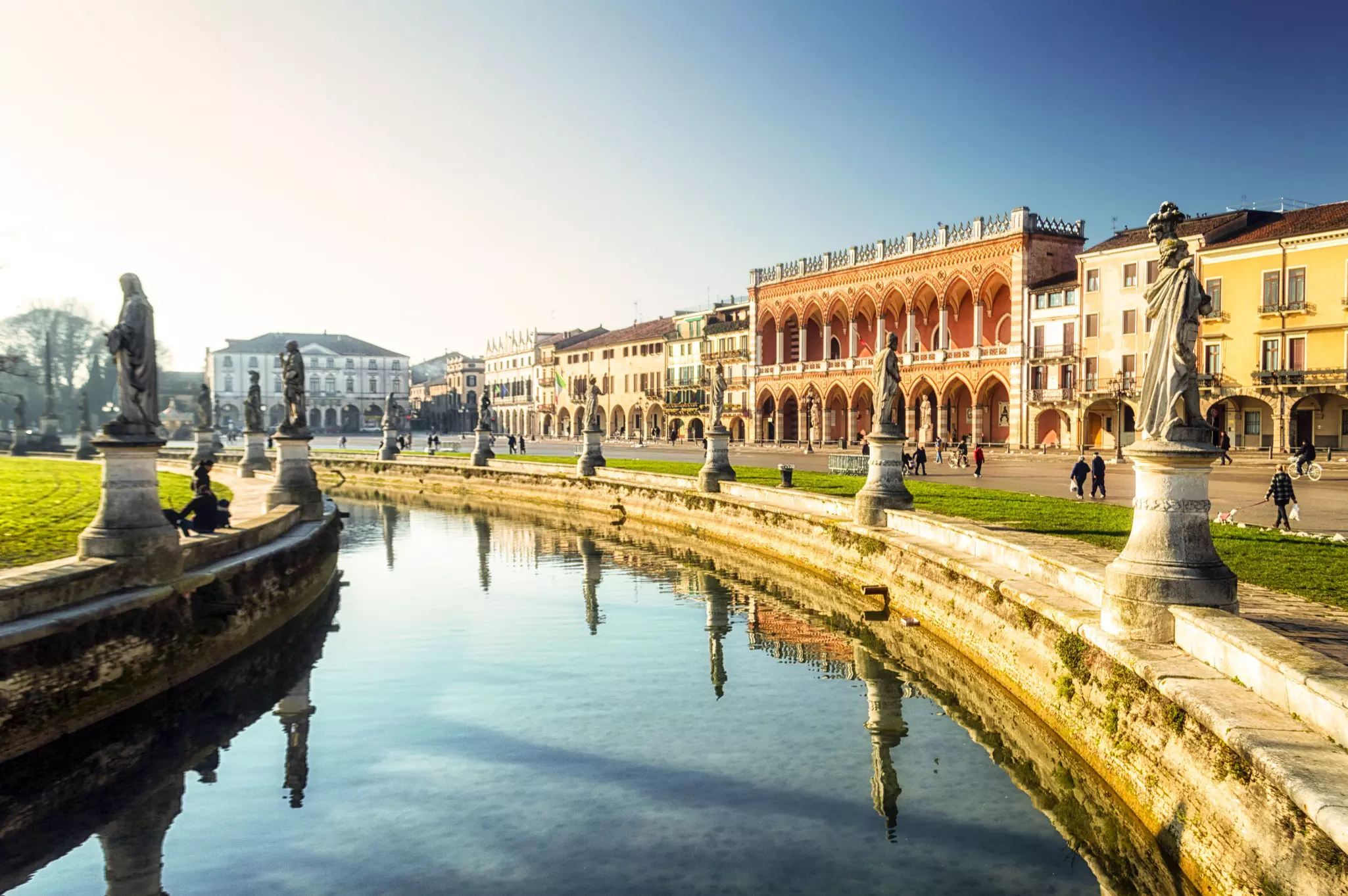 Buildings line a road that curves around a fountain in Italy.