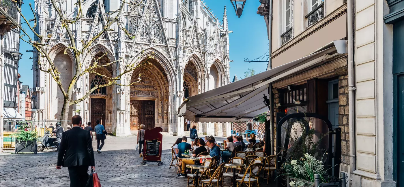People dine on the terrace of a bistro that is overlooked by a medieval church.