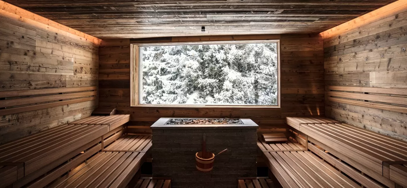 A sauna with a window looking out to snow-covered fir trees: Valsana Hotel, Switzerland