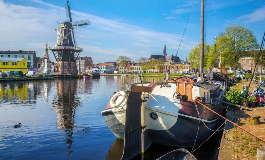 De Adriaan windmill beside the Spaarne river in Haarlem, a moored barge in front and St Bavo's spire beyond