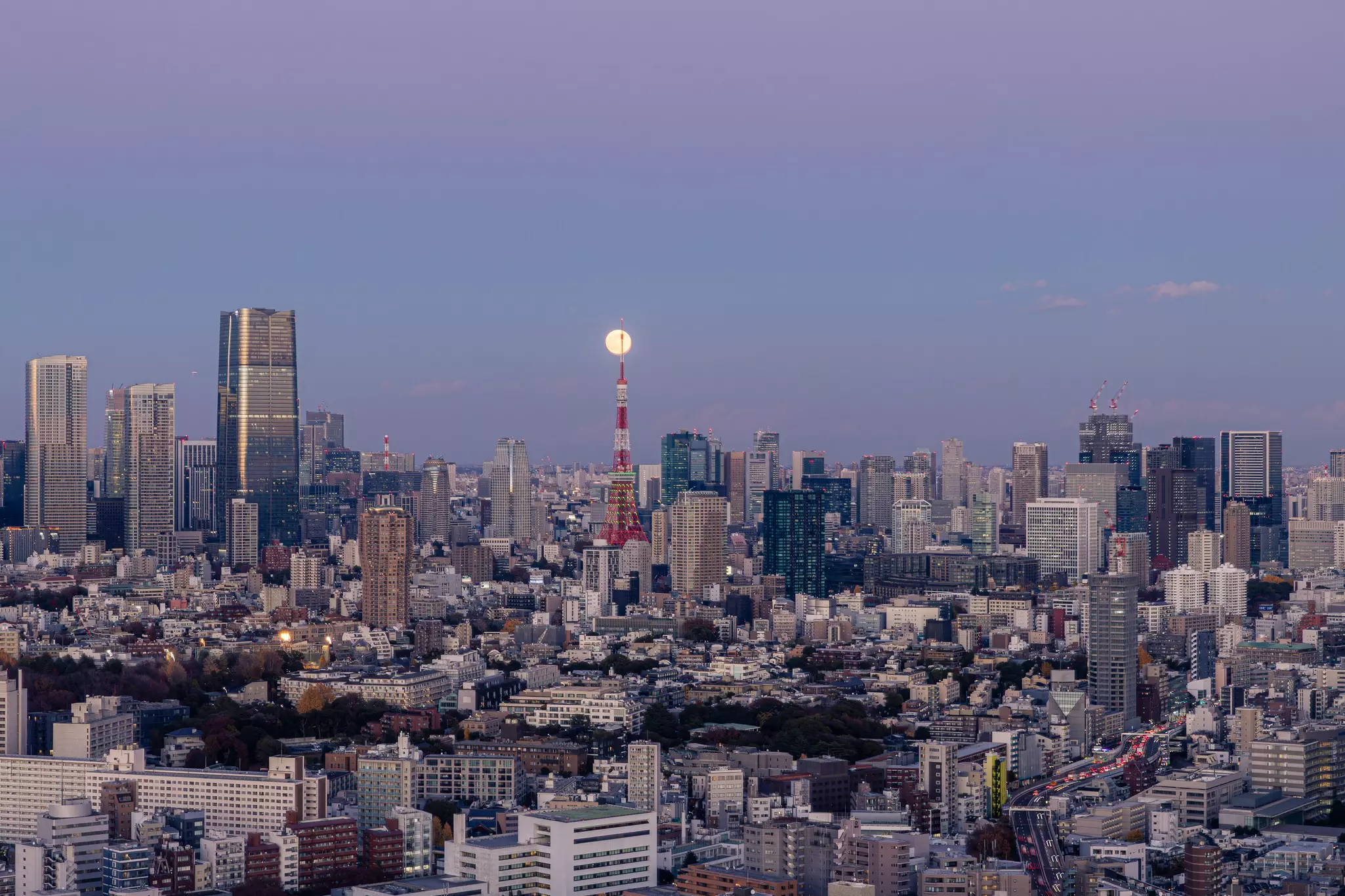 A full moon over a city skyline at night