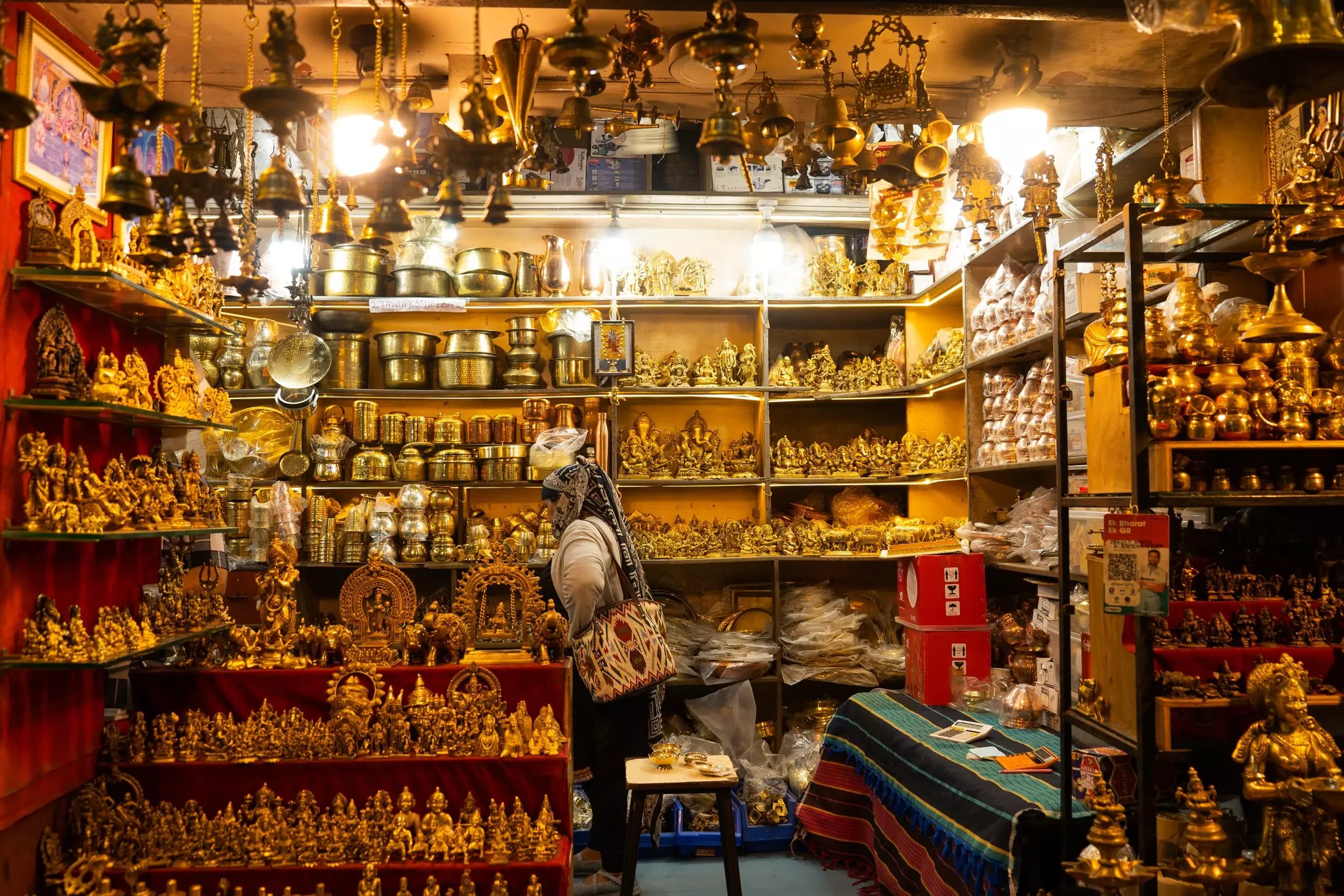 A person in a shop with shelves loaded with small sculptures and figurines.