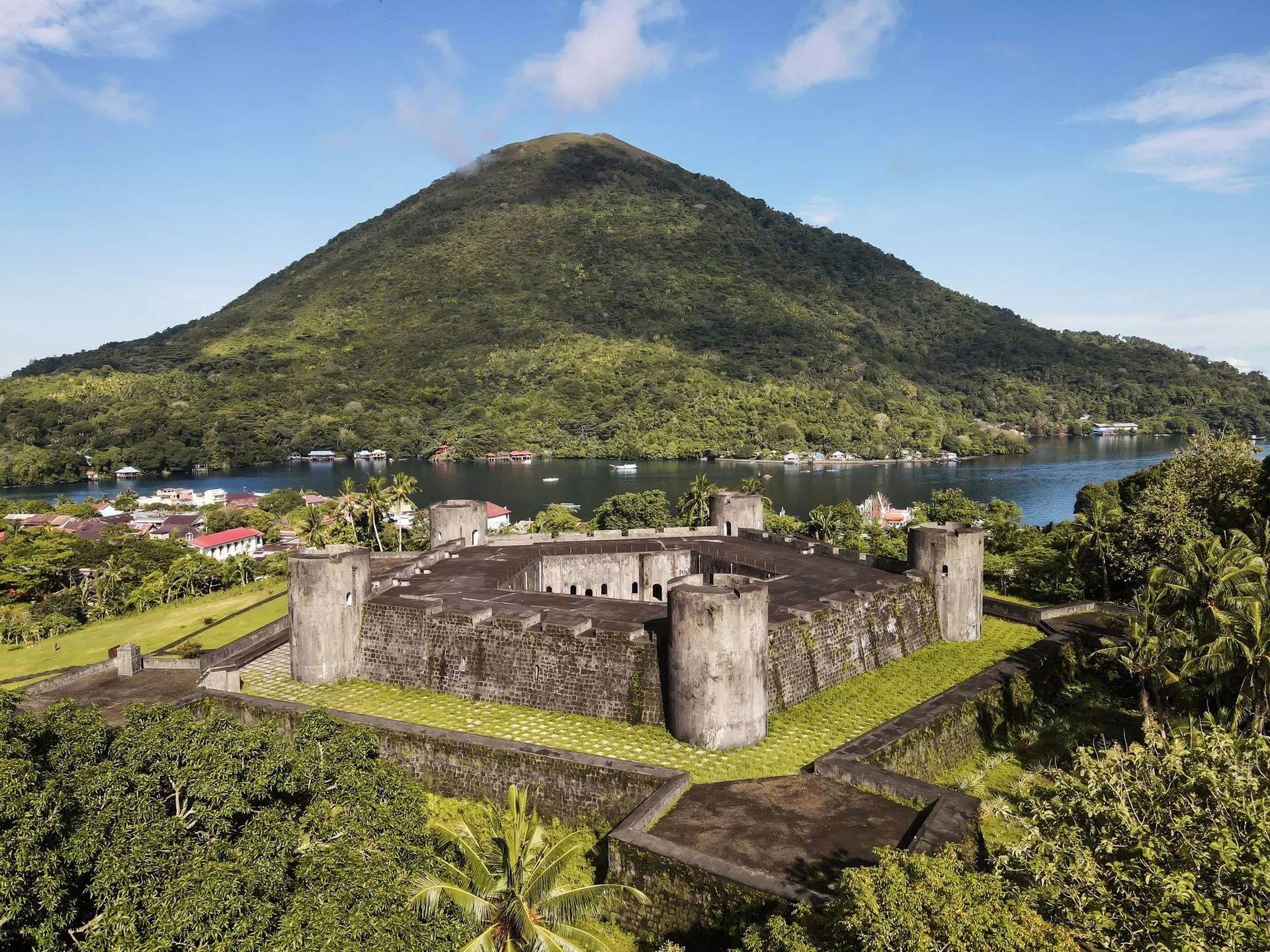 A large star-shaped fortress on a lush island near a volcano