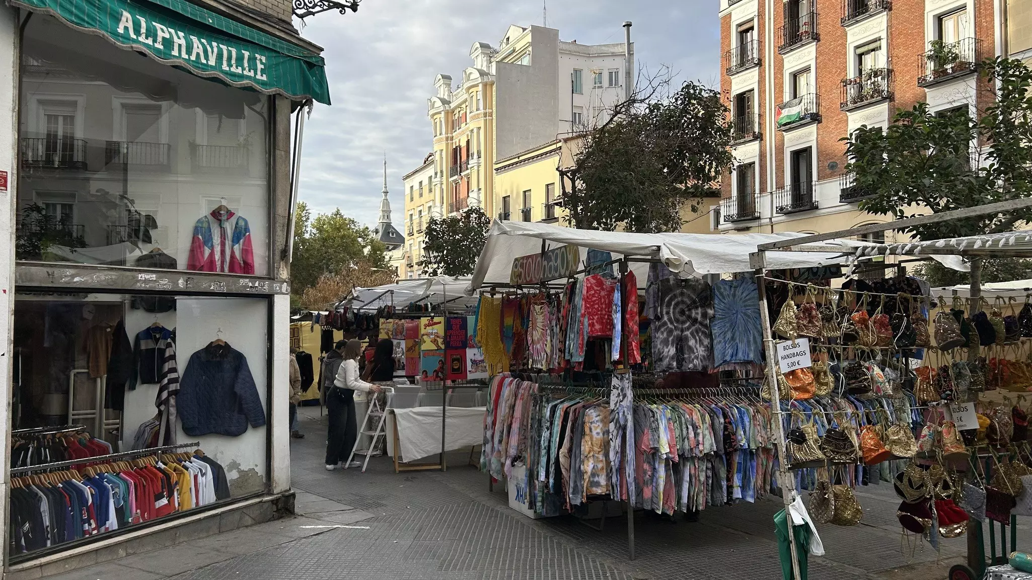 Clothing and other items hang on lines in booths at an outdoor market