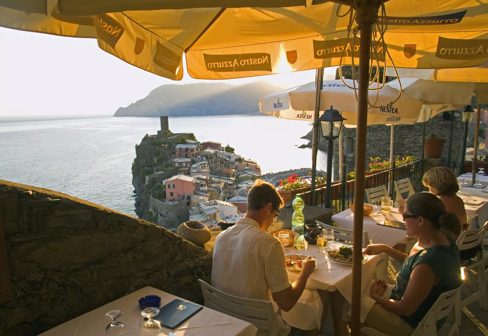 People eating on a clifftop restaurant terrace in Vernazza overlooking a small promontory and the ocean