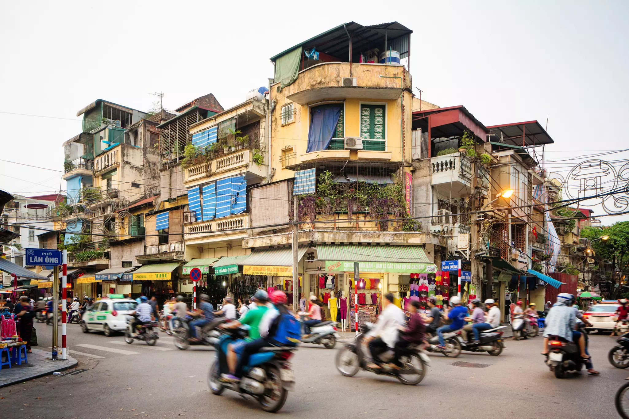 A busy city street in Hanoi filled with motorcycles and cars whizzing by