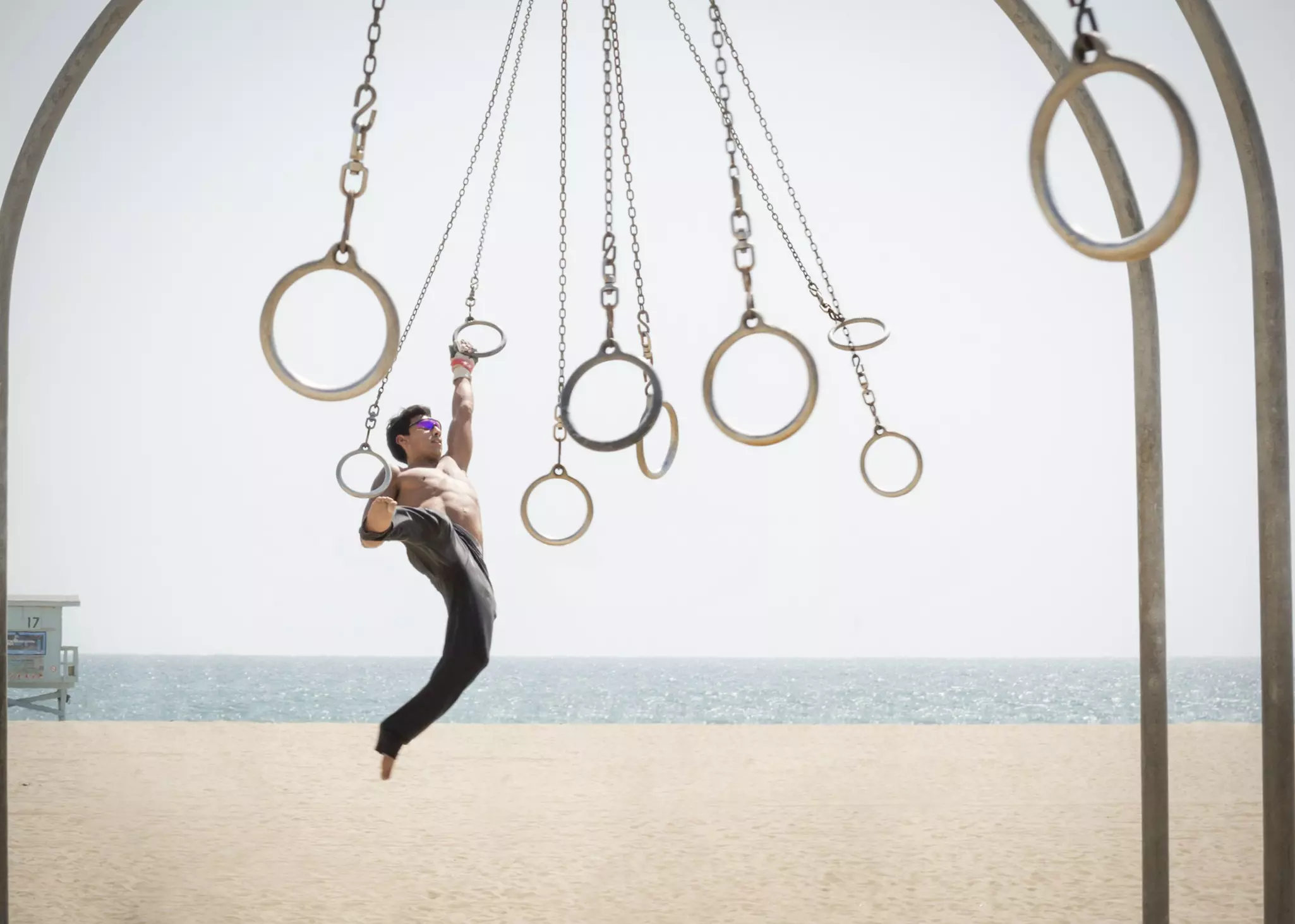 Man swings on suspended rings at an outside gym near Santa Monica beach