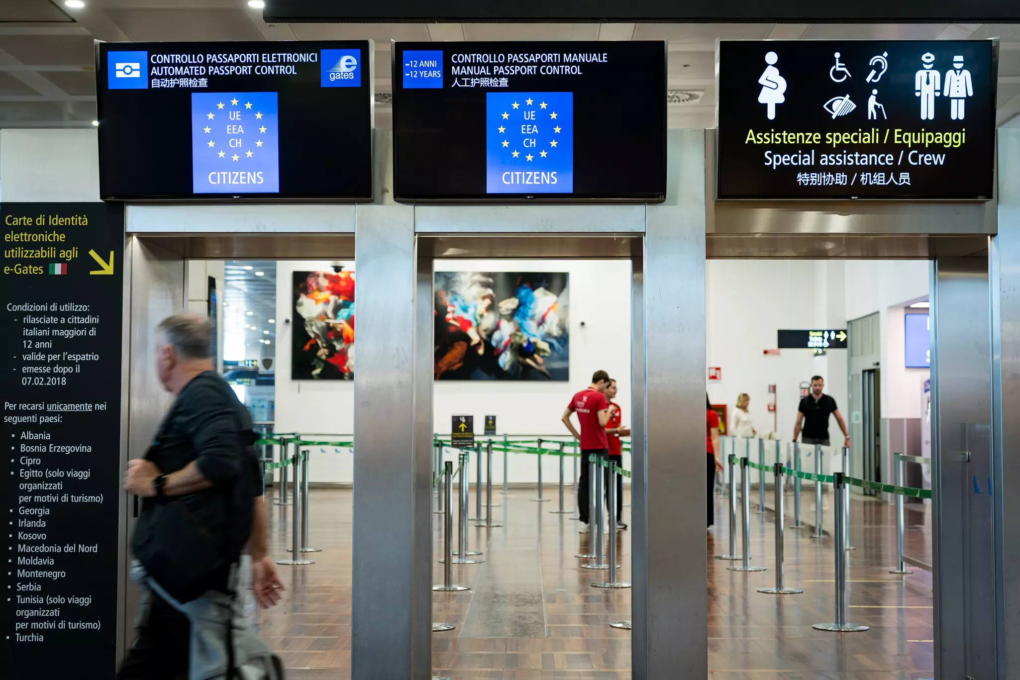 People are seen approaching gates for passport control at an international airport.