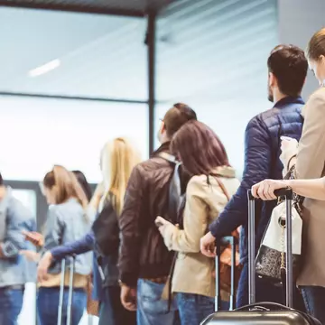 Crowds of people stand in an airport waiting.