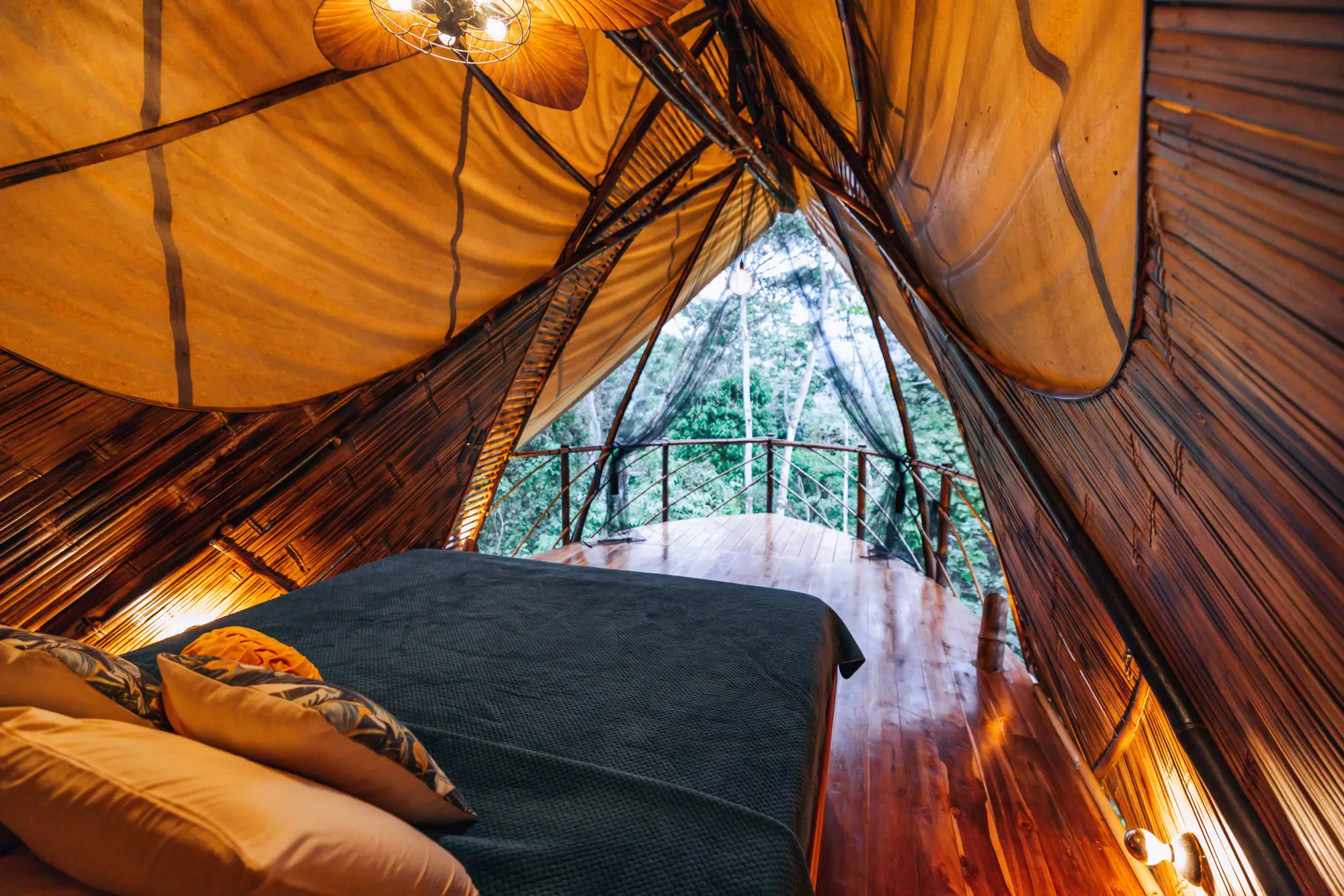 A bamboo cabin with a large double bed at the edge of the jungle.
