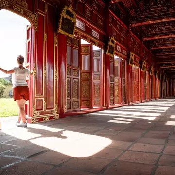 A tourist gazes out of the red and gold gates of the Imperial City of Hue, Vietnam.