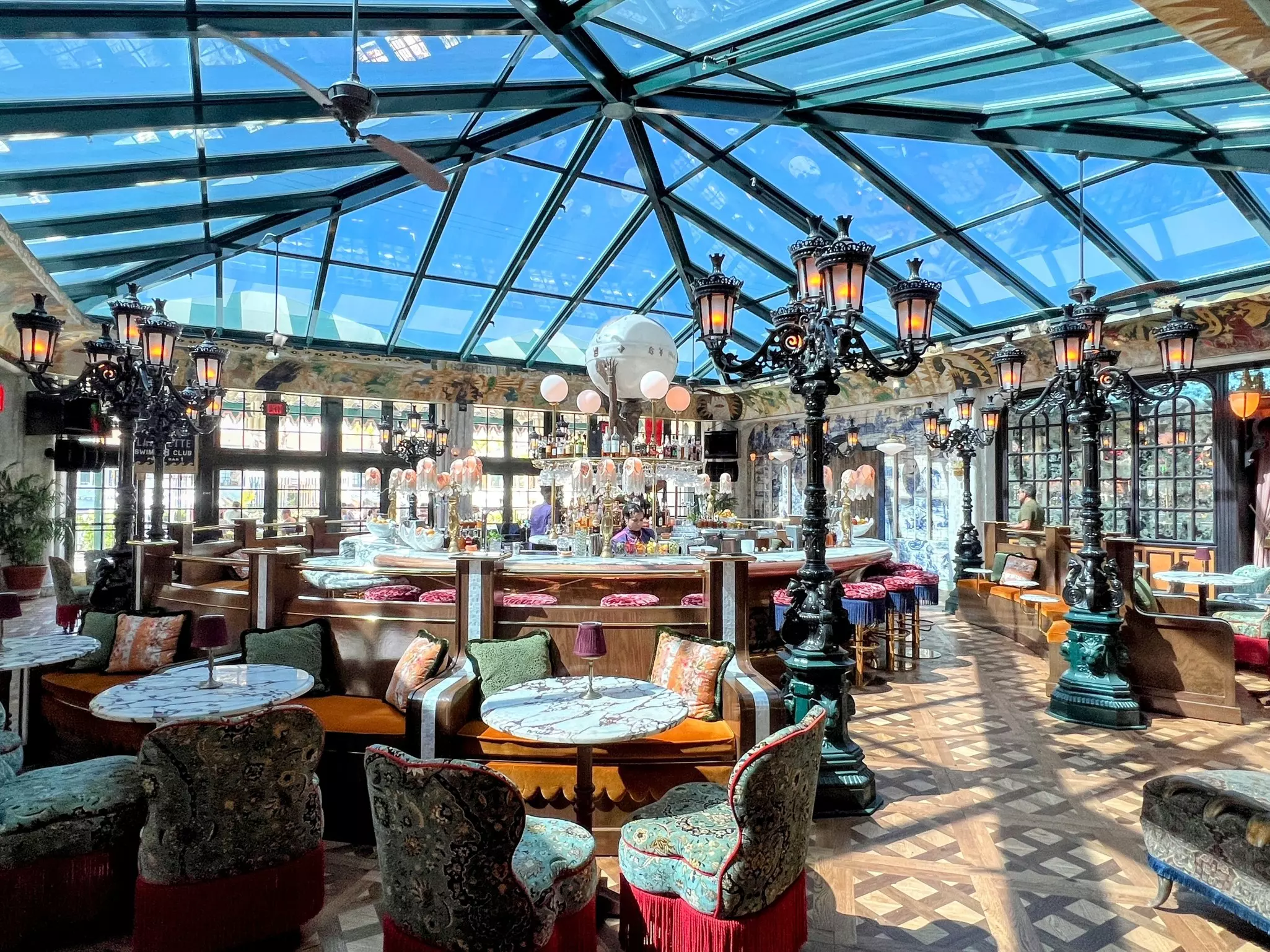A stylish restaurant in a hotel, with a glass conservatory roof and 1940s-style decor