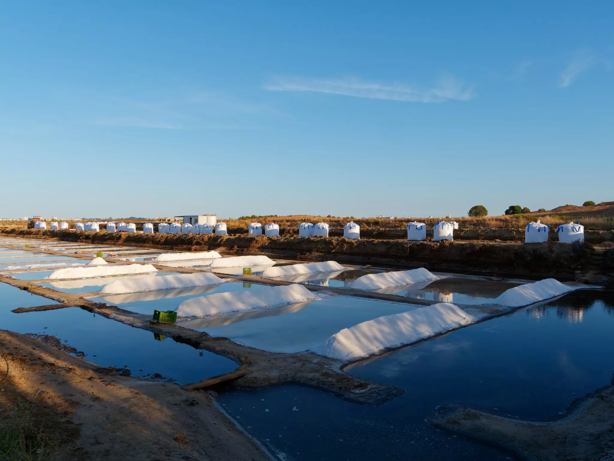 Long piles of white salt between rectangular pools of water.