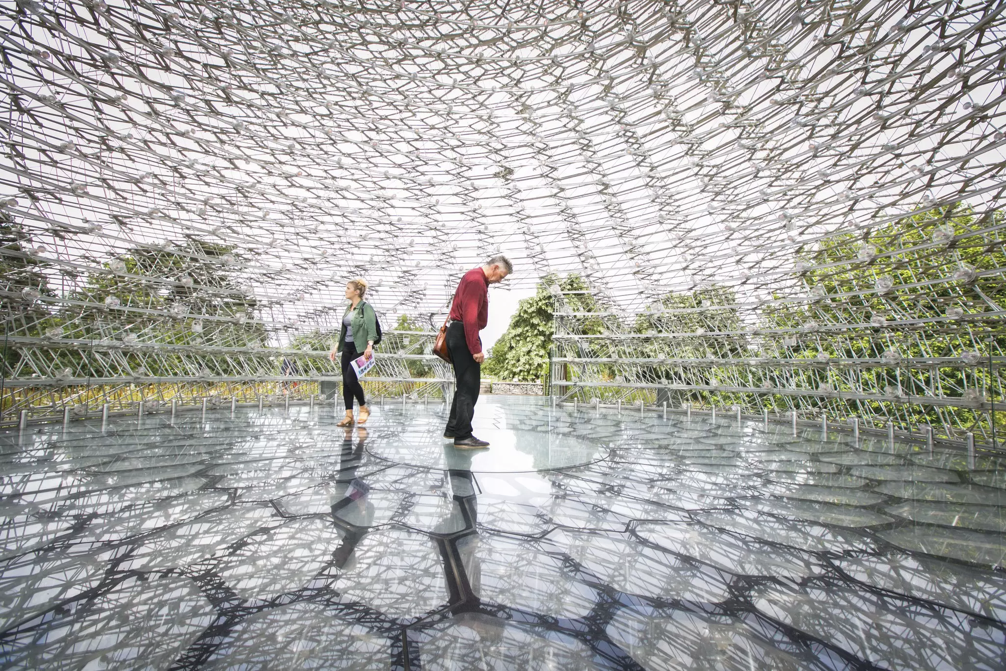 Two people stand in a large metal sculpture surrounded by honeycomb shapes
