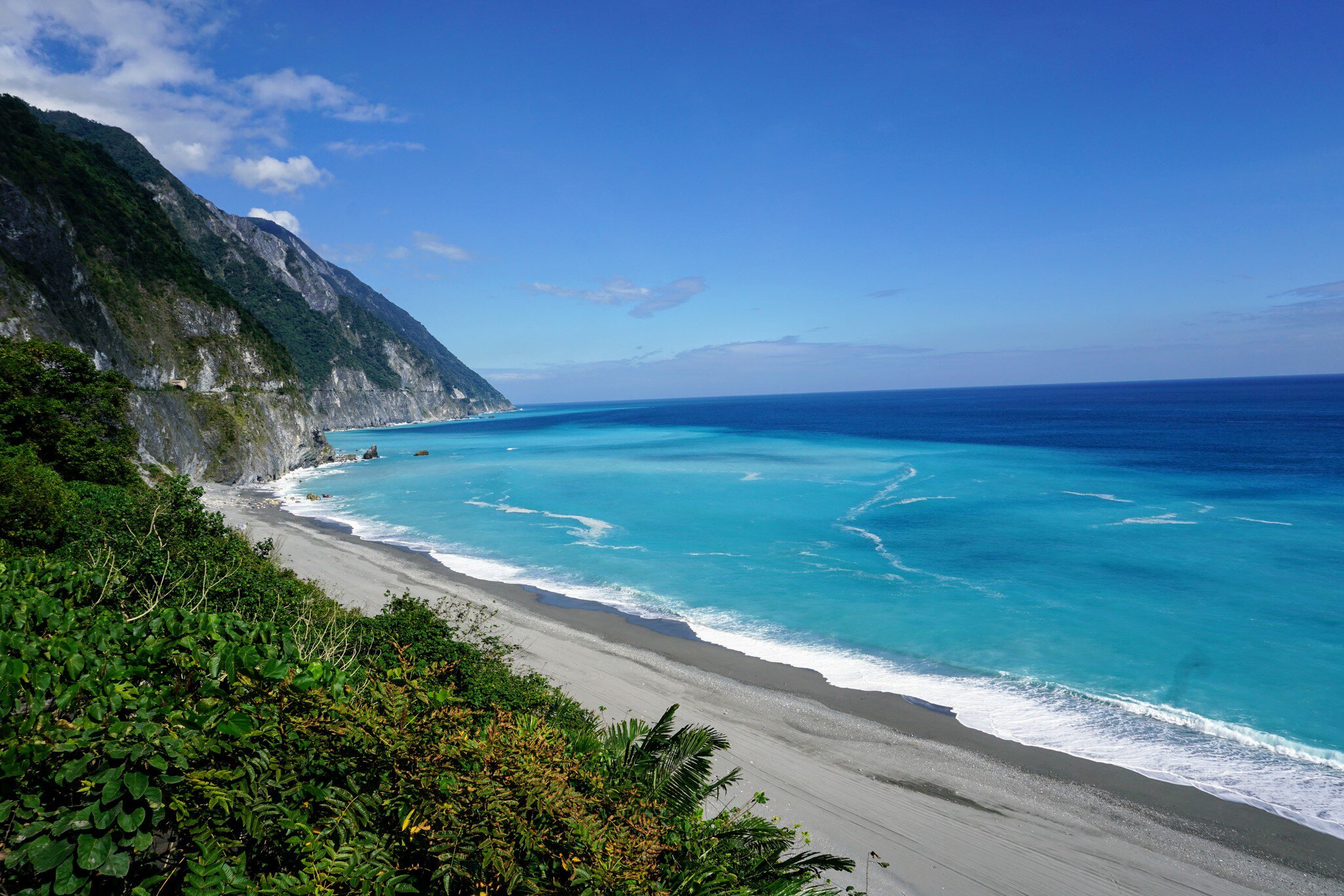 Qingshui Cliffs, sheer rock faces that drop into turquoise water, with a grey-sand beach, near Taroko National Park, Taiwan.