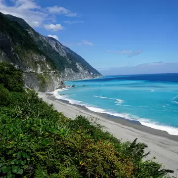 Qingshui Cliffs, sheer rock faces that drop into turquoise water, with a grey-sand beach, near Taroko National Park, Taiwan.