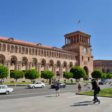 Pink tuff Government House with its clock tower and Armenian flag on Republic Square in Yerevan, Armenia