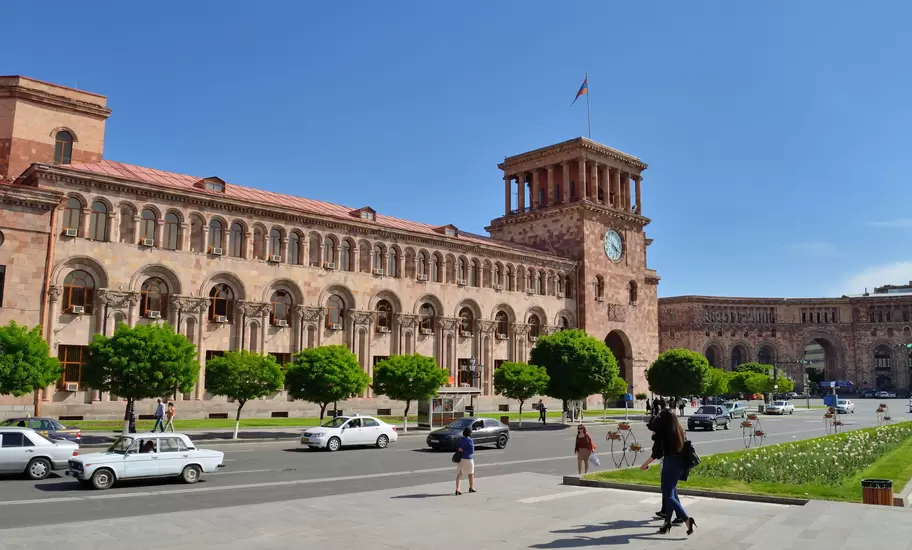 Pink tuff Government House with its clock tower and Armenian flag on Republic Square in Yerevan, Armenia