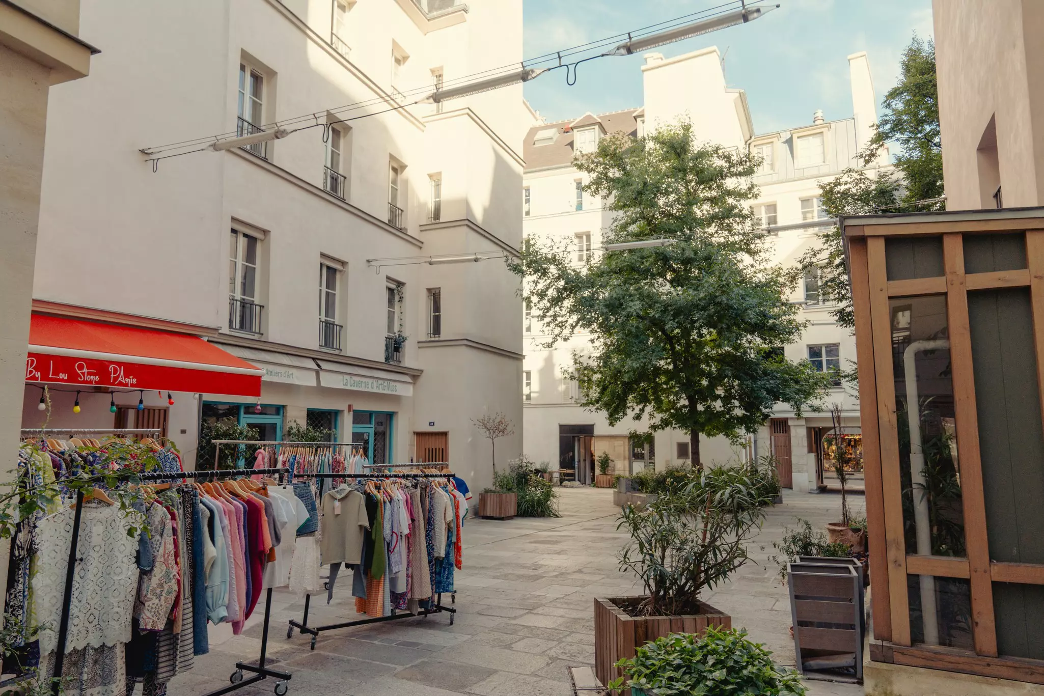 Clothes rails outside a boutique tucked down a pedestrian-only street in a city.