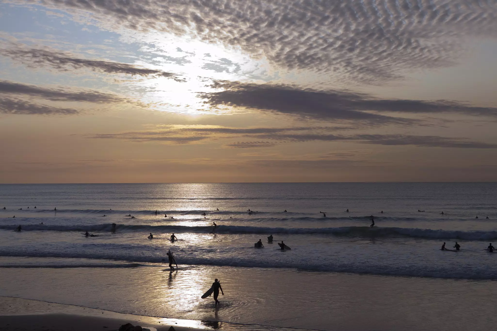 Surfers in the water at sunset in Newquay, Cornwall, England.