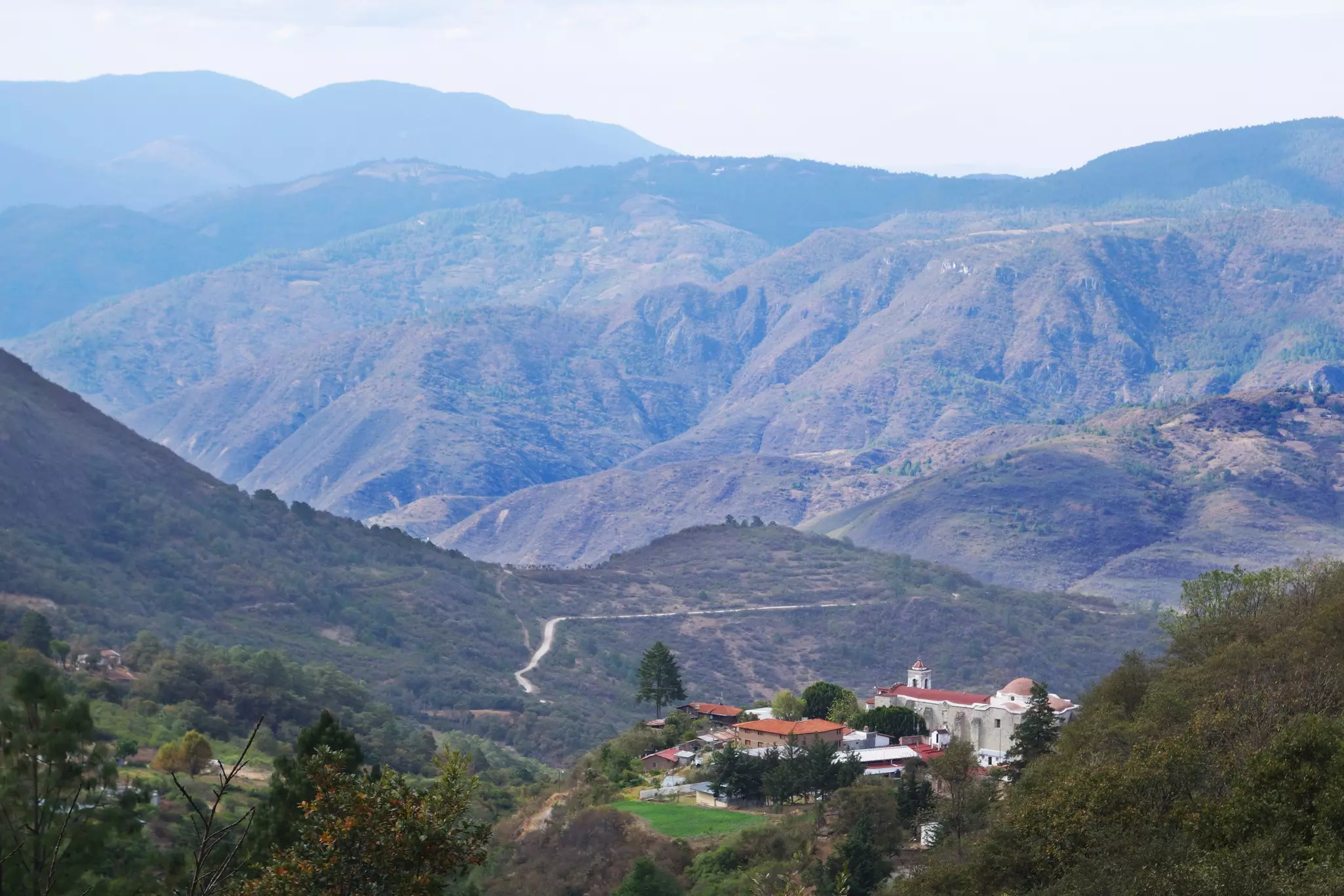 A tiny village tucked in the valley among rolling hills in a rural area.