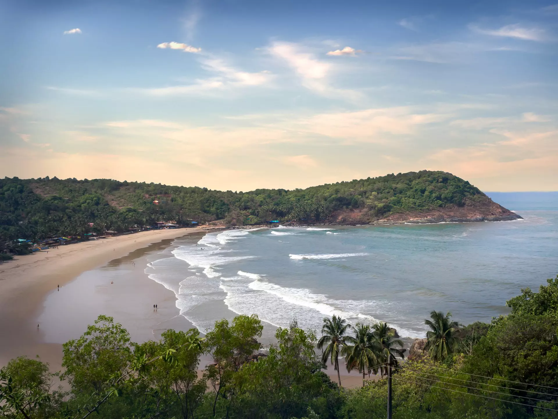 Horsehoe-shaped beach surrounded by cliffs covered in trees