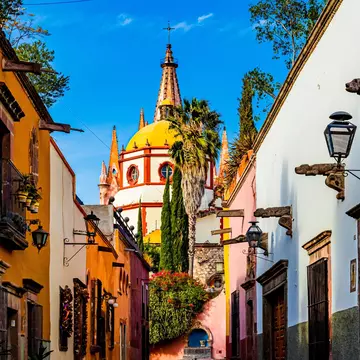 View down Calle Aldama, a famous cobblestone street in San Miguel de Allende, Mexico, with the view of the Parroquia de San Miguel Arcángel in the background.