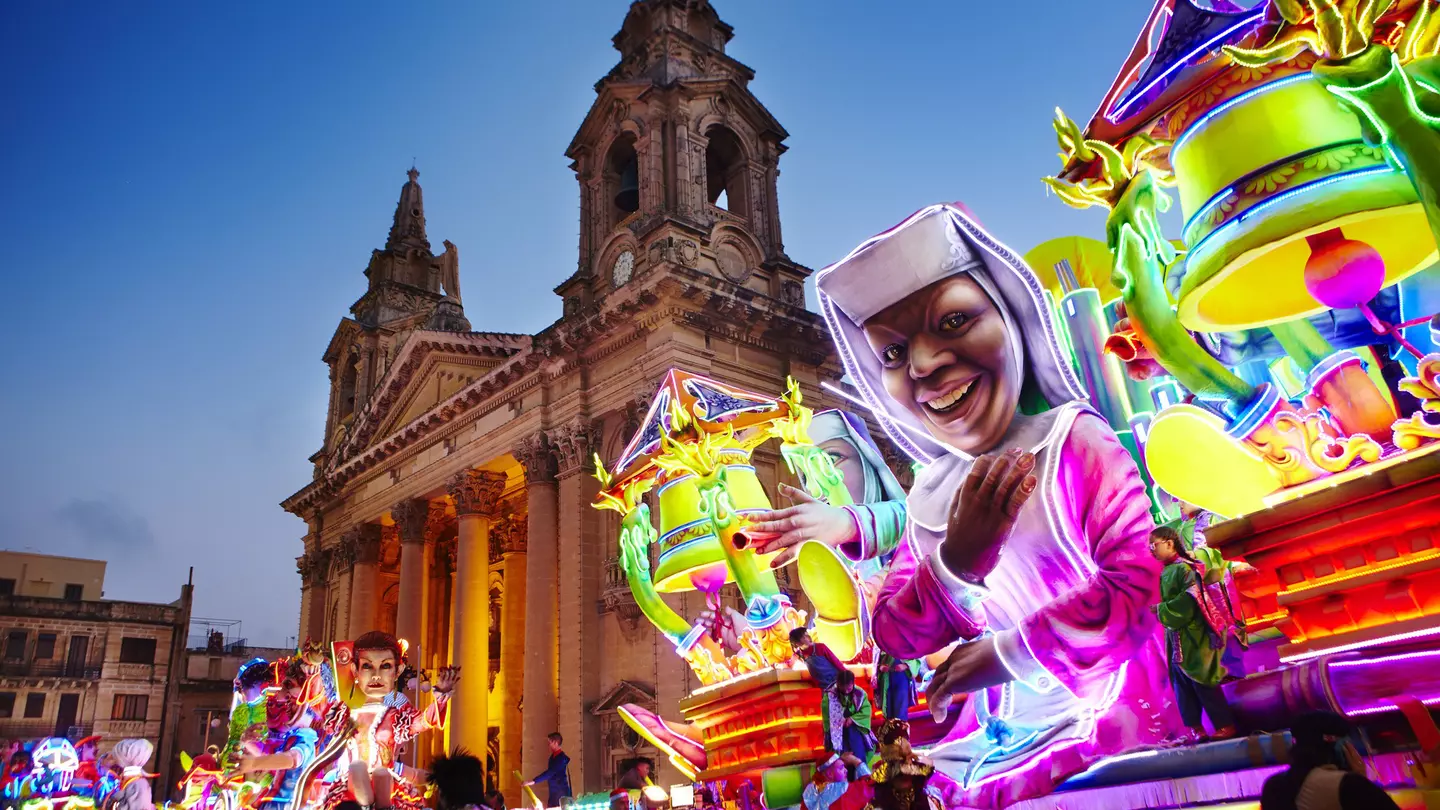 A neon-bright float inspired by the movie Sister Act passes by St Publius Parish Church in Floriana