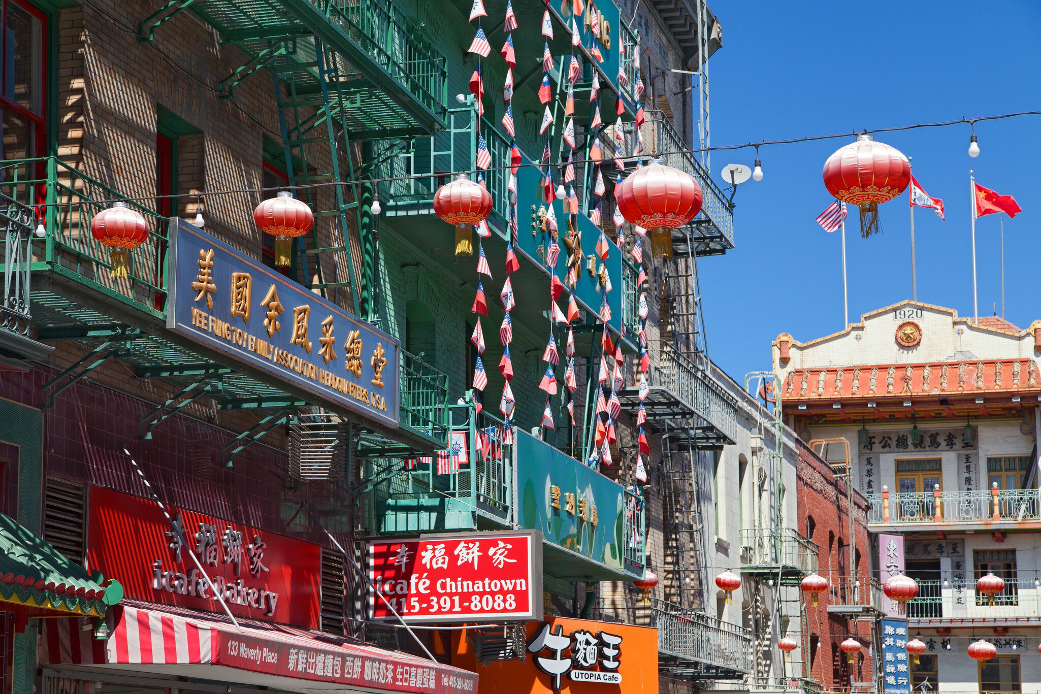 Green fire-escape balconies hung with red lanterns above Chinese shopfronts
