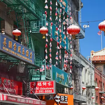 Green fire-escape balconies hung with red lanterns above Chinese shopfronts