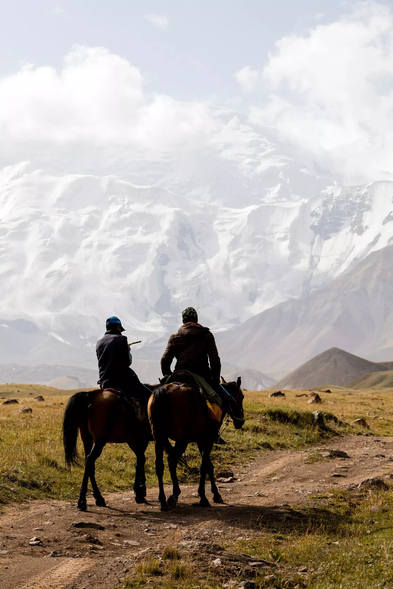 Two Kyrgyz riders ride their horses to base camp at the foot of Peak Lenin in Kyrgyzstan