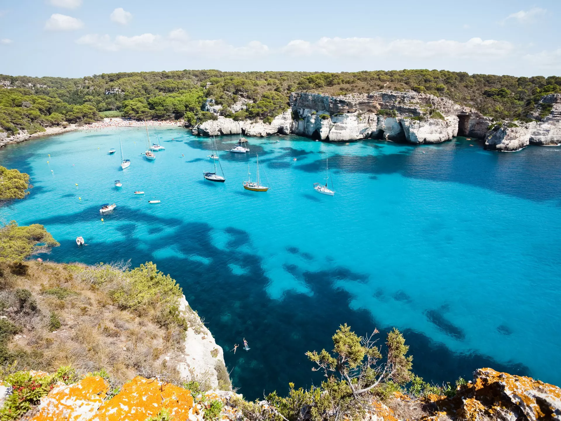 Cala Macarella, with boats floating in the clear waters.
