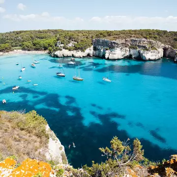 Cala Macarella, with boats floating in the clear waters.