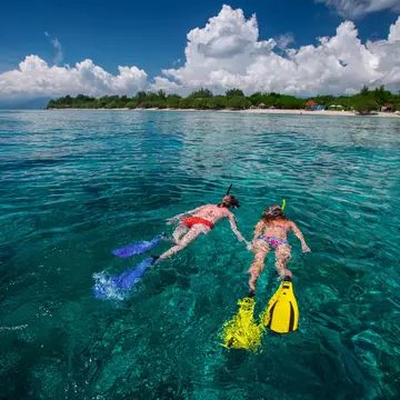 Two ladies snorkeling in a tropical, clear sea near Gili Trawangan island, Indonesia