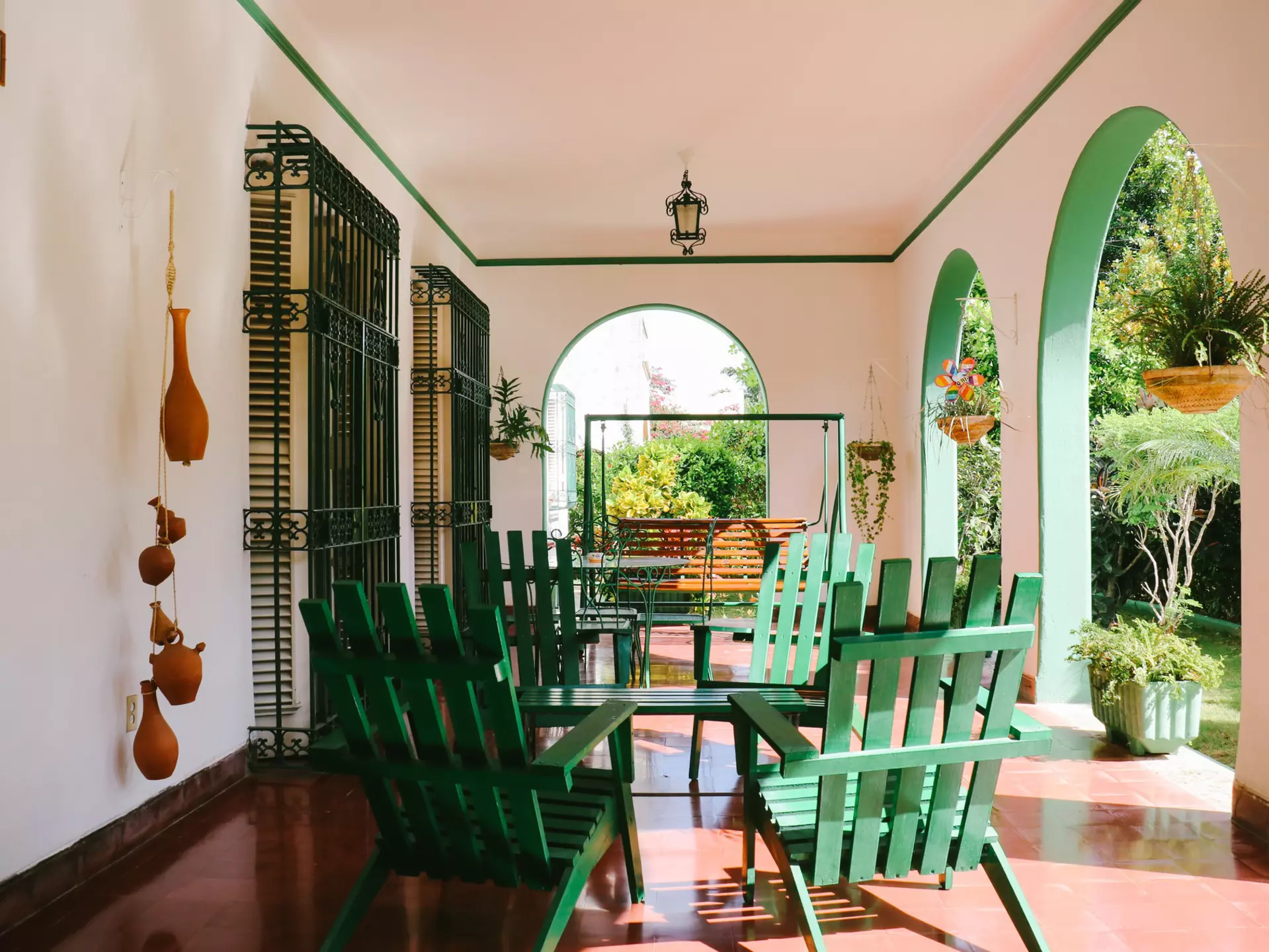 Chairs and a table on a veranda with arches in a city in the tropics.