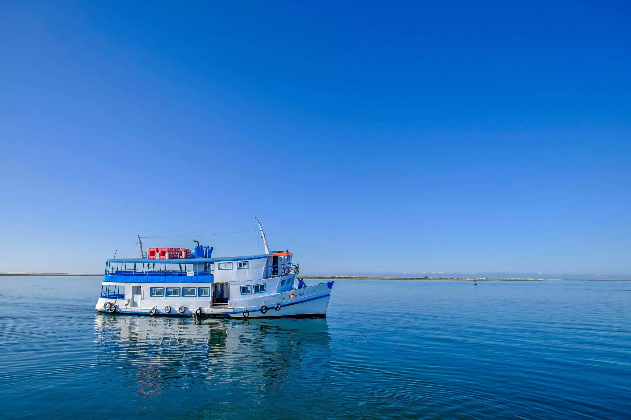 A white ferry with blue trim out in an ocean