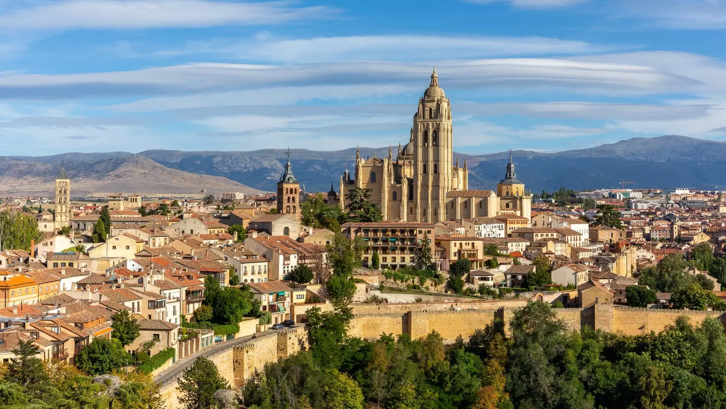 Segovia, Spain, cityscape panorama with Segovia Cathedral at the top, churches, medieval architecture, residential buildings city walls and mountains in the background. Aleksandra Tokarz / Shutterstock