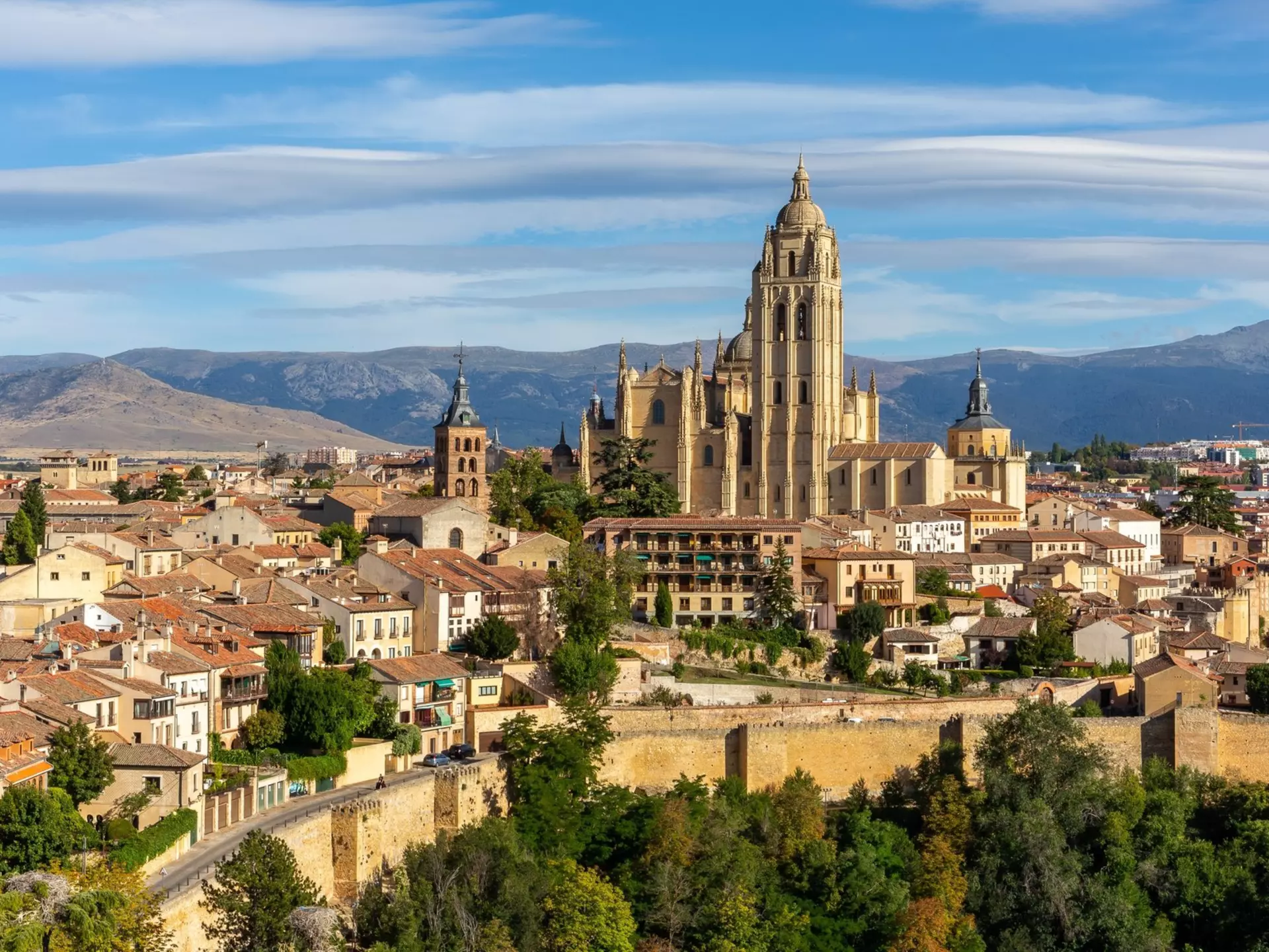 Segovia, Spain, cityscape panorama with Segovia Cathedral at the top, churches, medieval architecture, residential buildings city walls and mountains in the background. Aleksandra Tokarz / Shutterstock