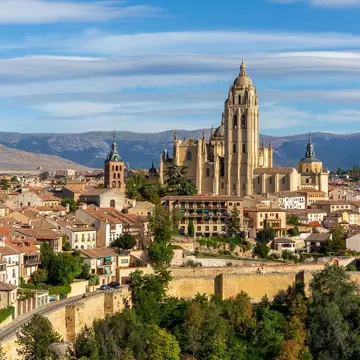 Segovia, Spain, cityscape panorama with Segovia Cathedral at the top, churches, medieval architecture, residential buildings city walls and mountains in the background. Aleksandra Tokarz / Shutterstock