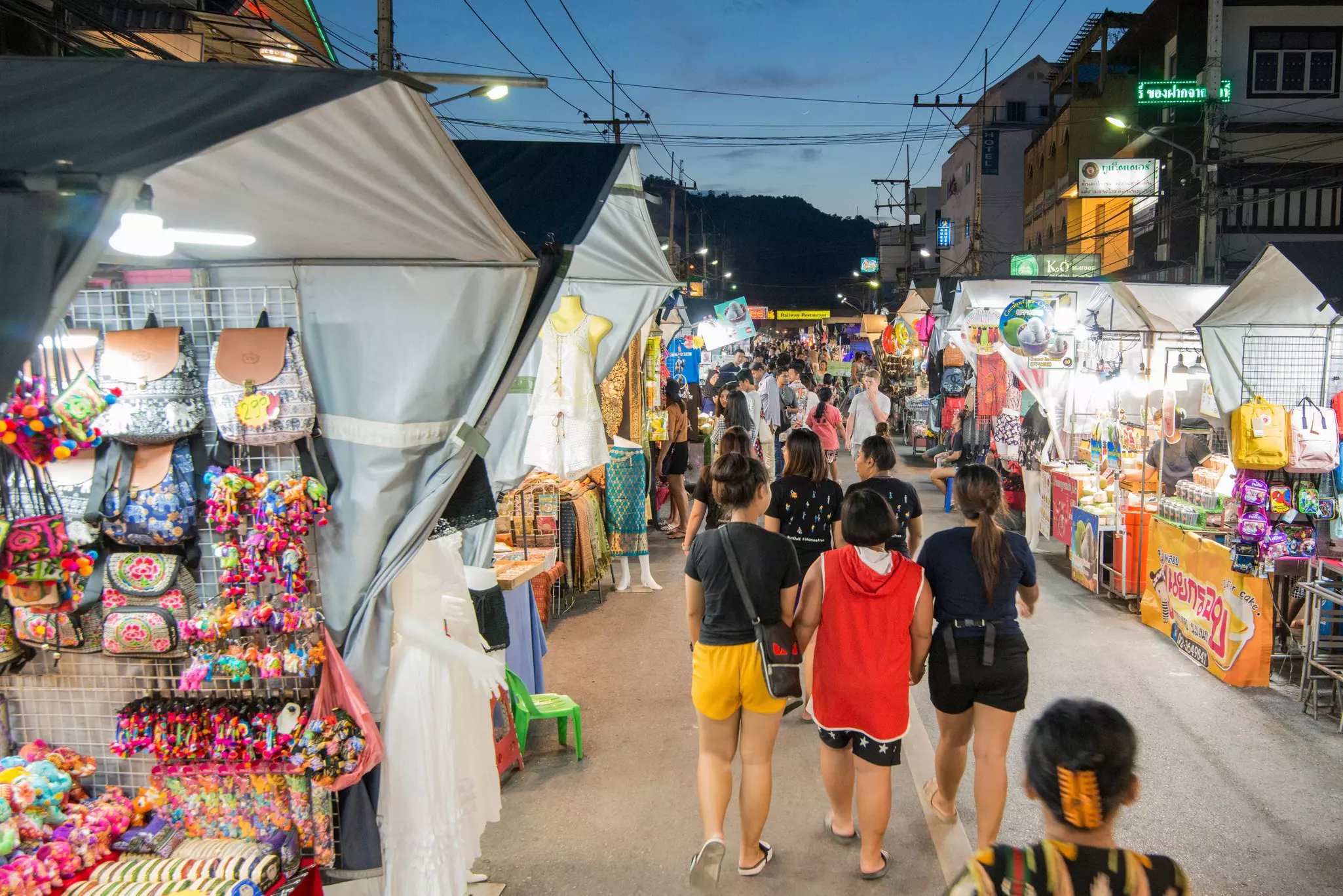 People walking through a market of souvenir and food vendors
