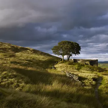 Ruins are seen on a grassy moorland under a stormy sky in West Yorkshire, England