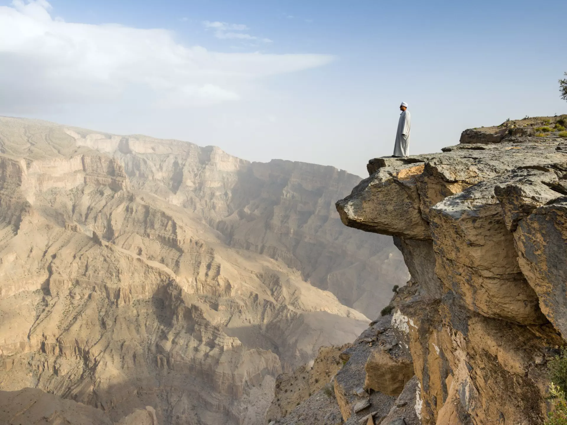 A local man fearlessly inspects Wadi Ghul,.the so-called ‘Grand Canyon of Arabia’, from the top of Jebel Shams