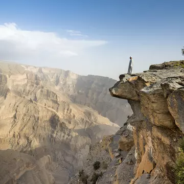 A local man fearlessly inspects Wadi Ghul,.the so-called ‘Grand Canyon of Arabia’, from the top of Jebel Shams