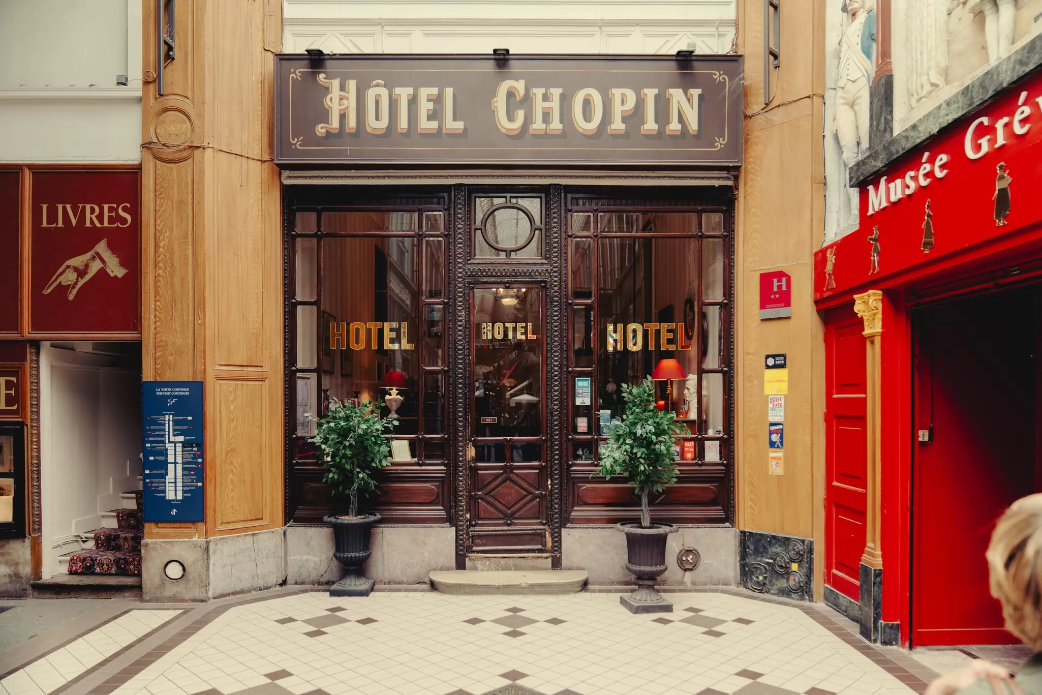 The indoor front door to a hotel with a sign that reads "Hotel Chopin." The facade is dark wood