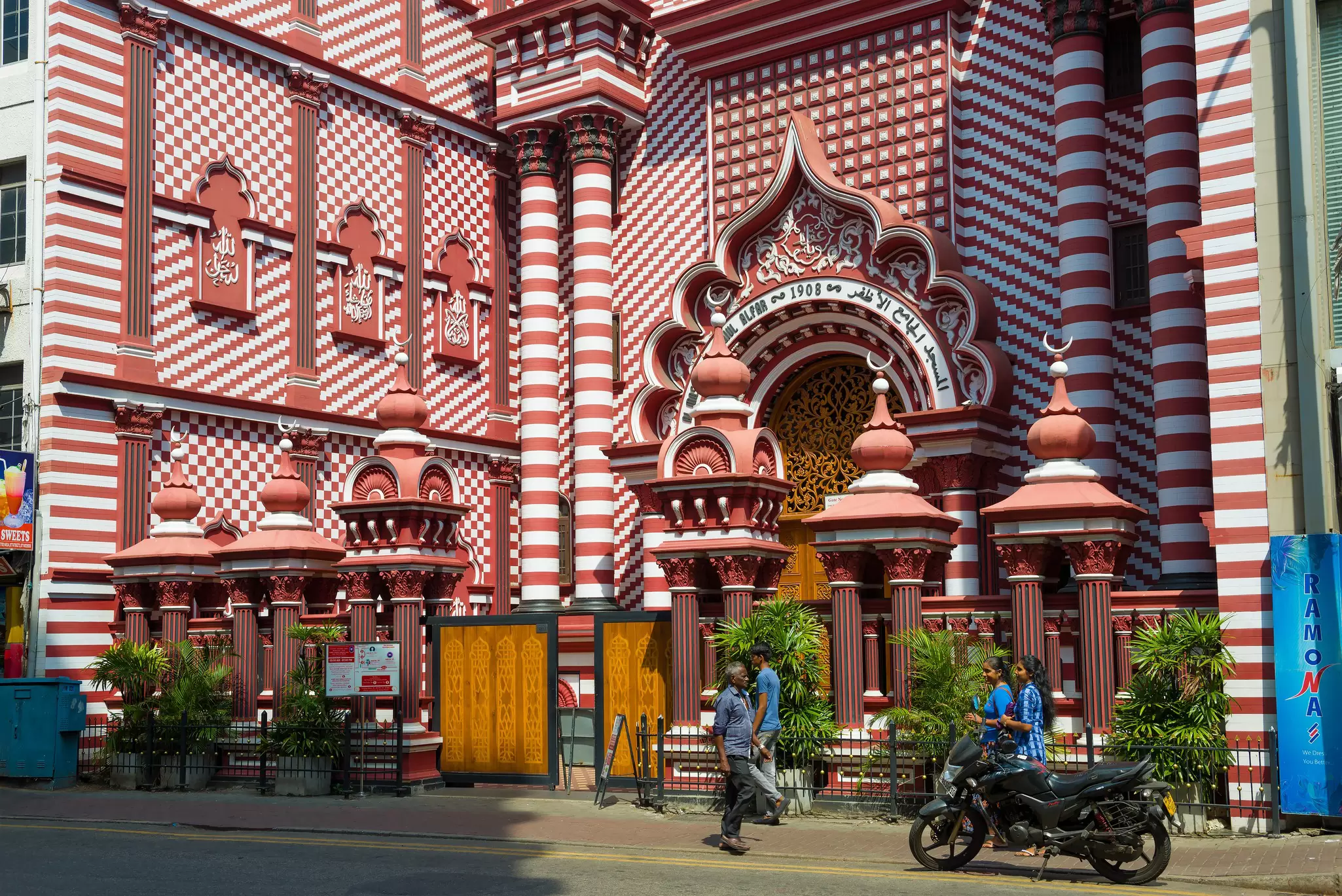 Front of a large mosque painted in red-and-white stripes