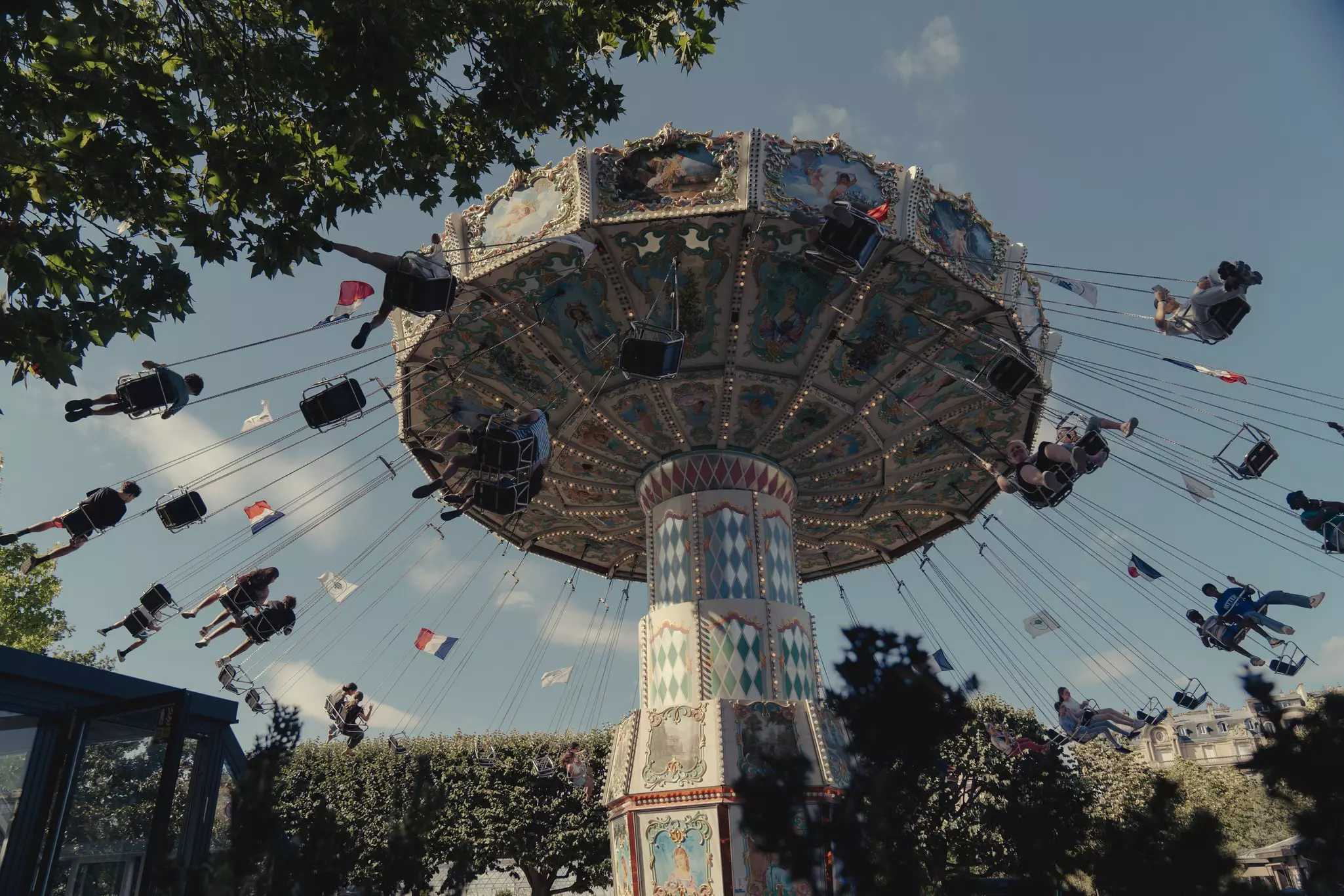 People on a swing-ride attraction at an amusement park, pictured from below.