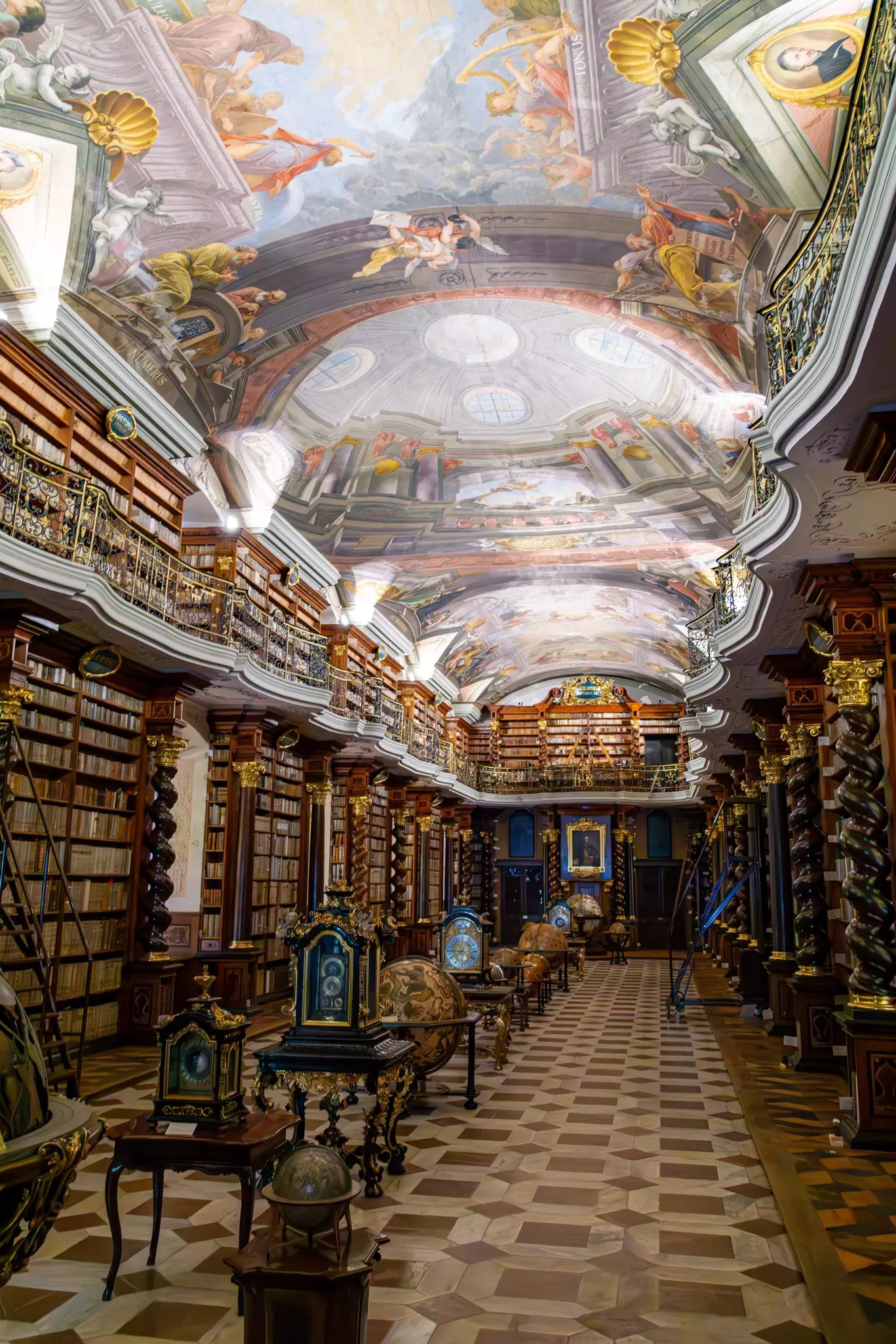 An old library with floor-to-ceiling bookshelves and figures painted in its ceiling