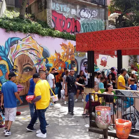 People congregate in a plaza covered with colorful graffiti in a Latin American city.