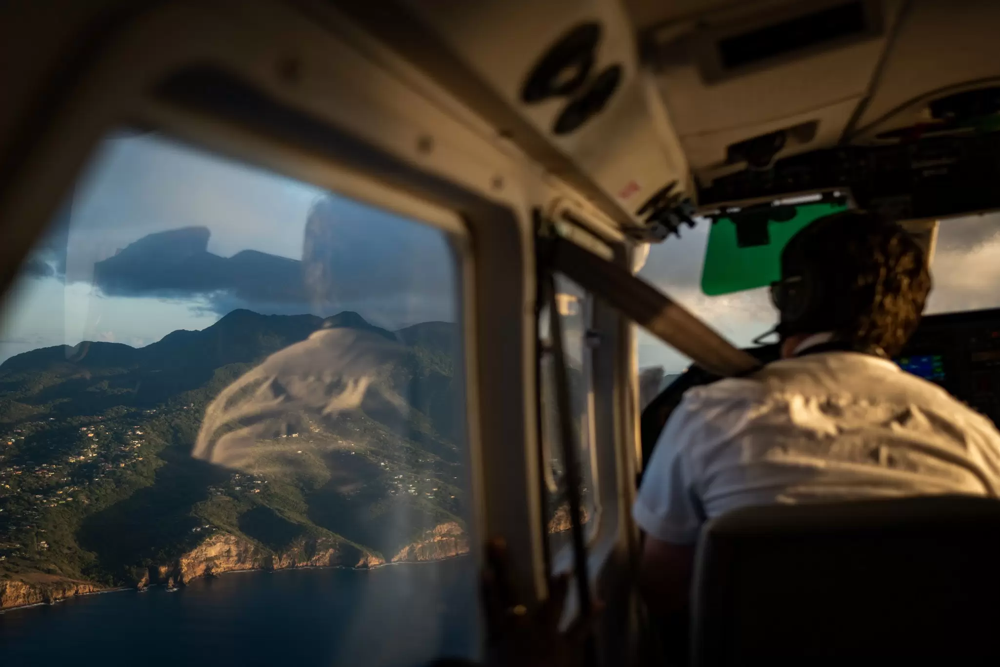 A view of the northwest side of the island from a Fly Montserrat small plane with the pilot in shot